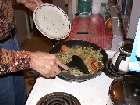 Paul adds the previously sauteed onions and bean sprouts and yam chips to browned liver for final cooking